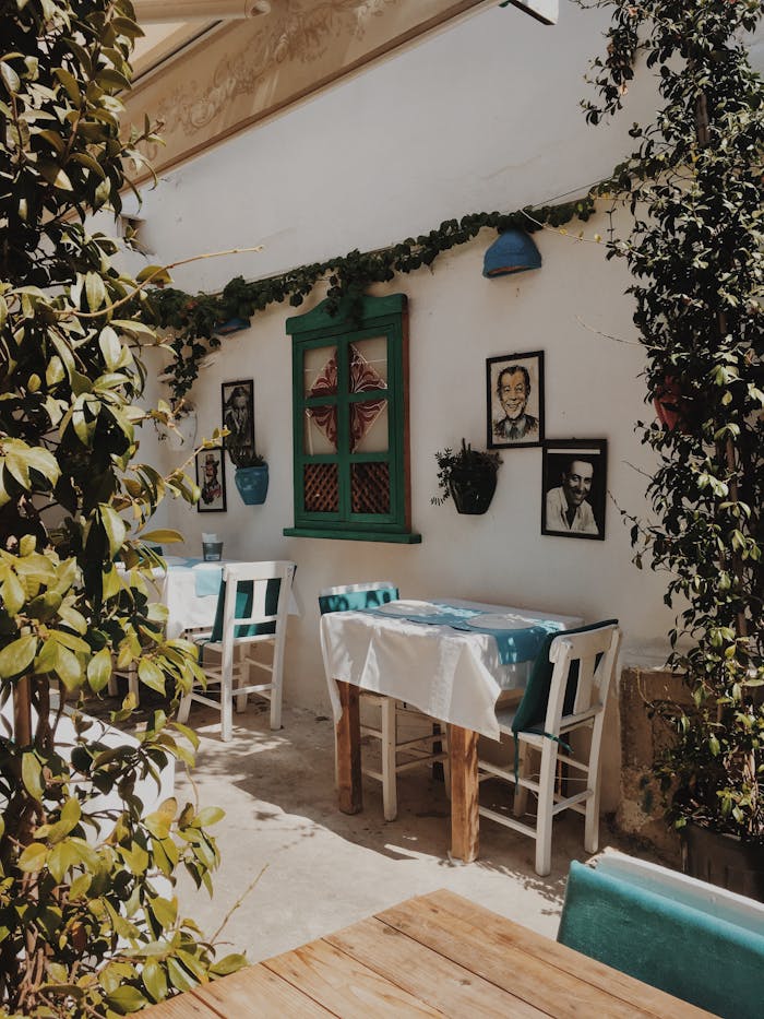 Home Rustic outdoor cafe scene in Çeşme, Türkiye with tables, chairs, and greenery.