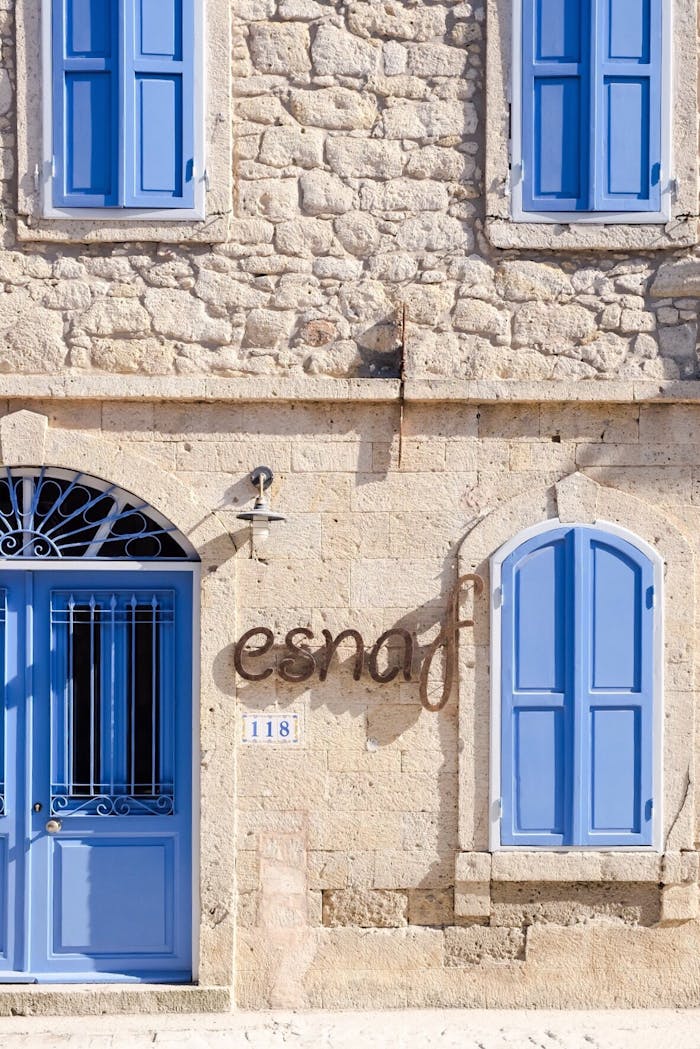 Crafting Captivating Headlines: Your awesome post title goes here A picturesque stone building in Alaçatı featuring vibrant blue windows and doors, exuding Mediterranean charm.